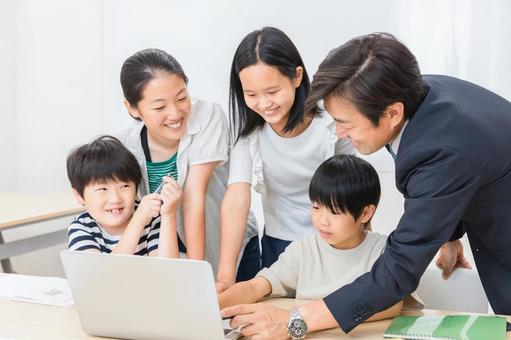 教室で先生と一緒に勉強する生徒のイメージ